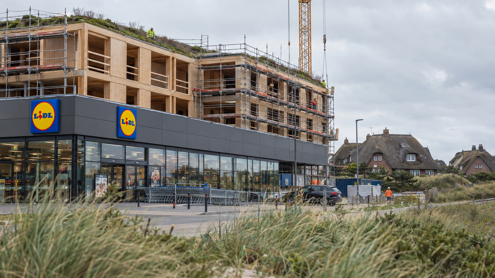 Rohbau auf Sylt: Lidl-Filiale im Erdgeschoss, Wohnungen im Bau darüber, Reetdachhäuser im Hintergrund